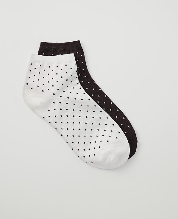 A pair of white and dark brown polka dot ankle socks lie on a plain white background.