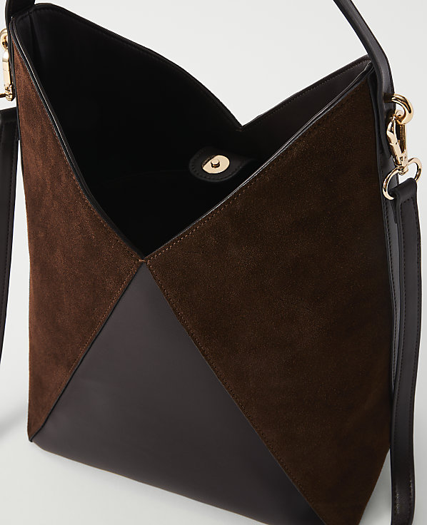A brown suede and leather handbag with a gold clasp is shown against a plain white background.