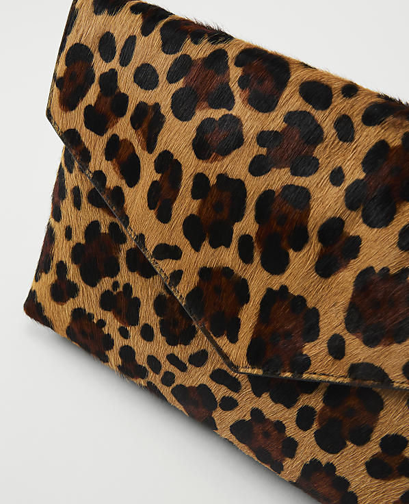 A leopard-print clutch bag with a textured fur-like surface is angled against a plain white background.