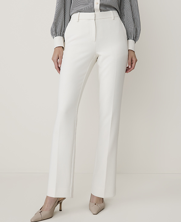 A person in white flared trousers and a striped blouse stands against a plain white background.