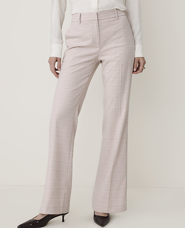 A person stands in the foreground wearing light pink plaid dress pants and a white blouse, against a plain, light-colored background.
