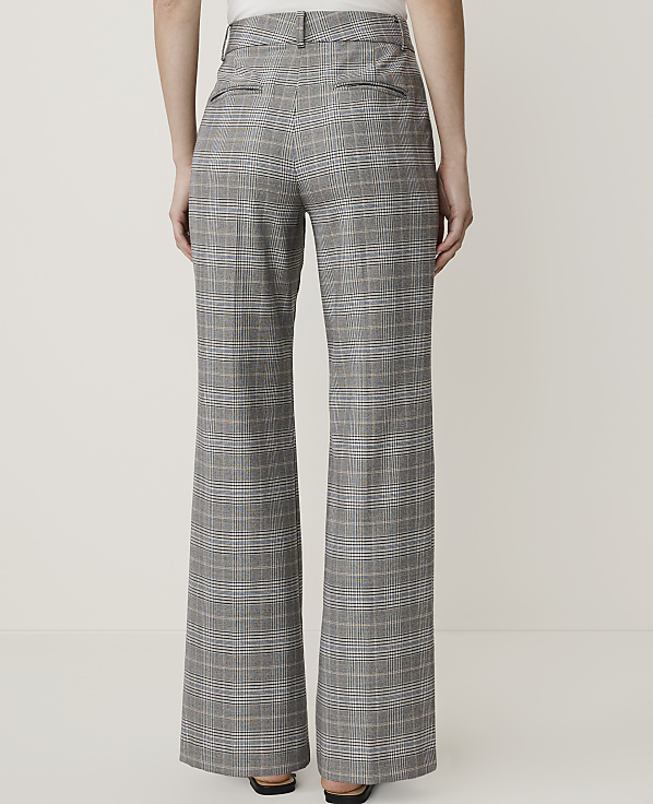 A person wearing high-waisted, wide-leg plaid pants stands against a plain white background.