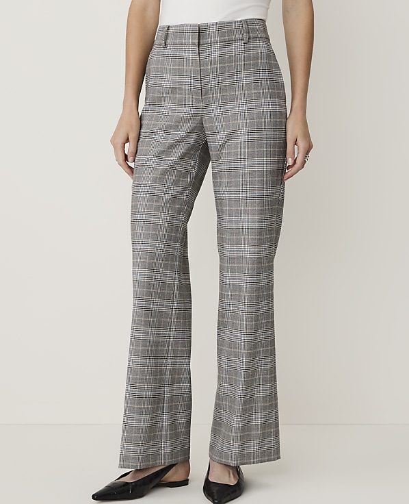 A person wearing plaid flared pants and black flats stands against a plain, light-colored background.