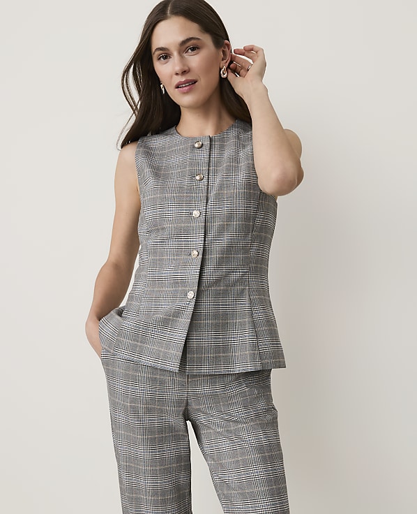 A woman in a plaid vest and pants stands against a plain white background.