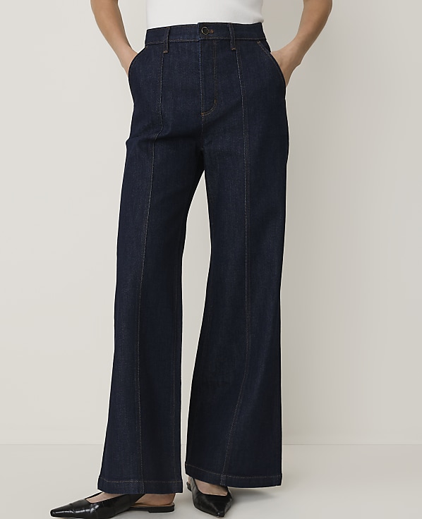 Dark wash flared jeans with a white top and black pointed-toe flats are displayed against a plain white background.