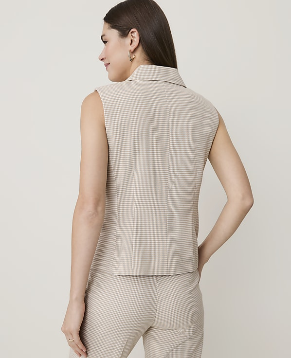 A woman in a patterned sleeveless top and pants stands against a plain, light-colored background.