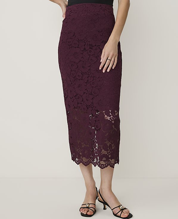 A woman in a burgundy lace pencil skirt and black heels stands against a plain white background.