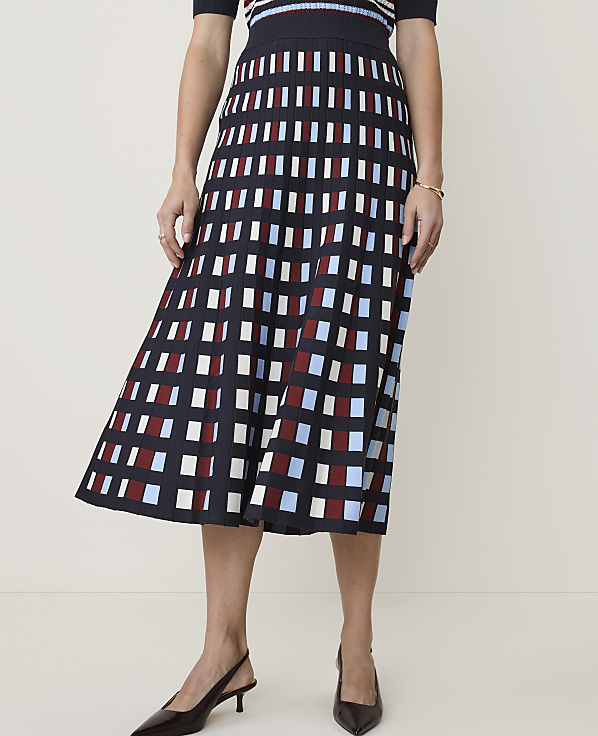 A woman in a patterned skirt and heels stands against a plain background.