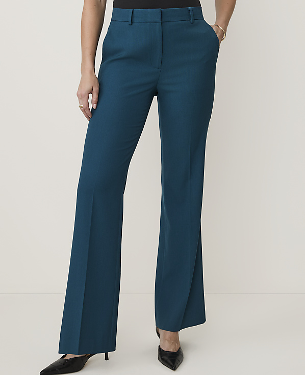 A person stands in teal flared trousers and black heels against a plain white background.
