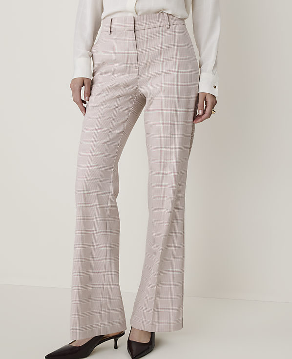 A person in a white blouse and plaid flared pants stands against a plain white background.