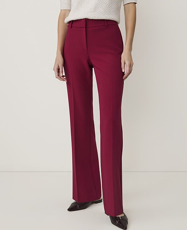 A person in burgundy flared trousers and a cream-colored top stands against a plain white background.
