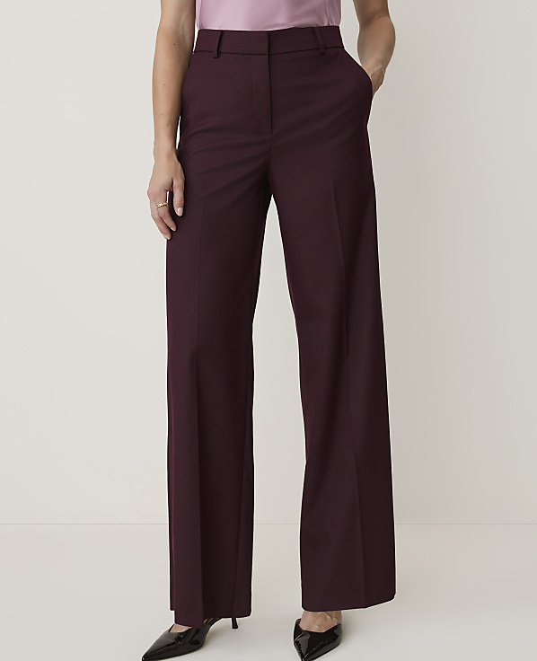 A person in burgundy wide-leg trousers and a pink top stands against a plain white background.