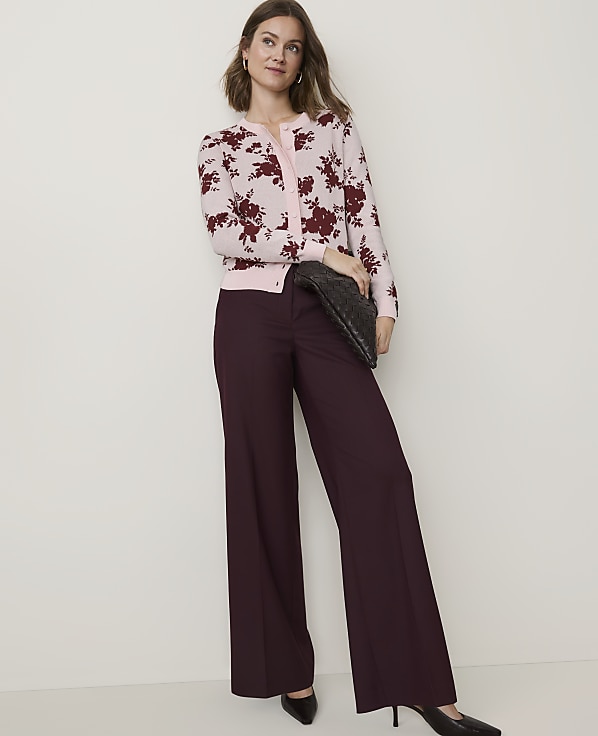 A woman in a floral cardigan and wide-leg pants poses against a plain background.