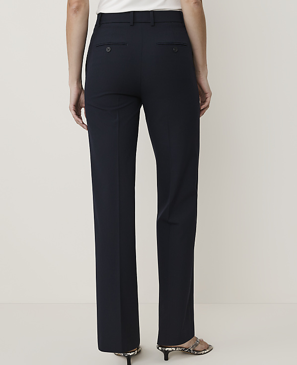 A person wearing dark navy trousers stands against a plain, light-colored background.