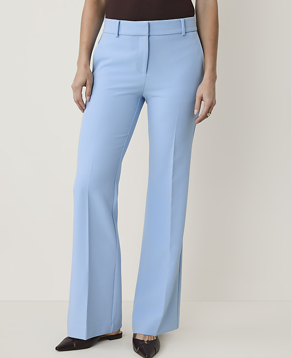 A person stands in light blue flared trousers and dark shoes against a plain white background.