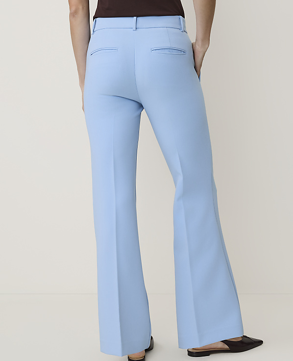 A person wearing light blue flared pants stands against a plain, light-colored background.