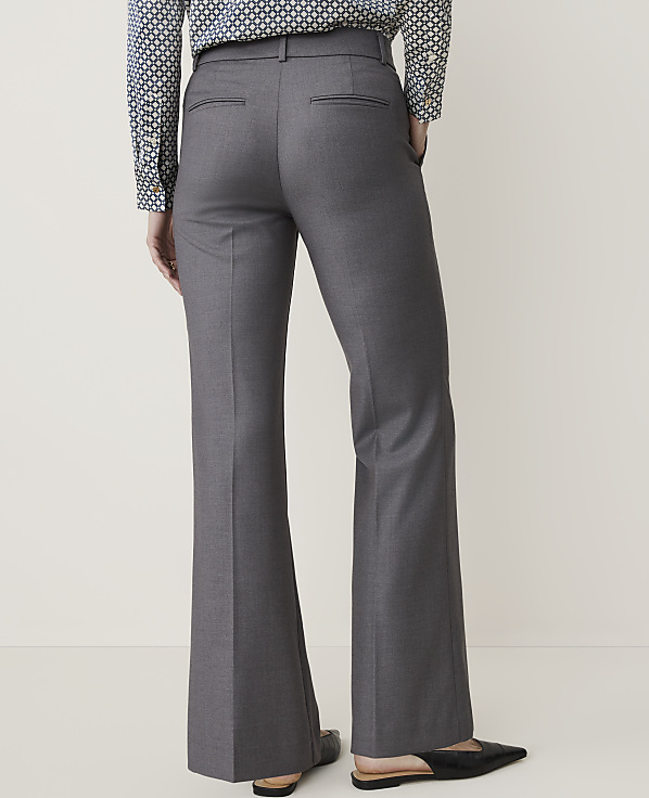 A person wearing gray flared trousers and a patterned shirt stands against a plain, light-colored background.