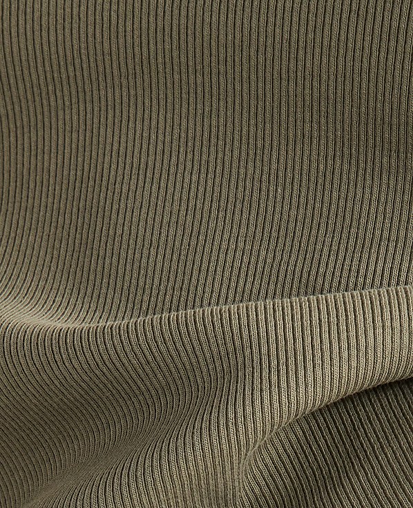 A close-up view of olive green ribbed fabric shows a folded section in the foreground against a backdrop of more of the same textured material.