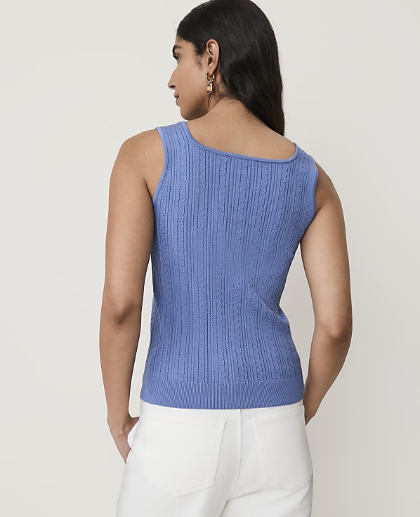 A woman in a blue knit top stands against a plain white background.