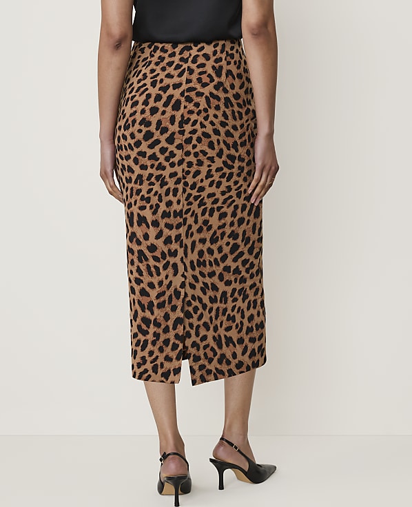 A woman in a leopard print skirt and black heels stands against a plain, light-colored background.