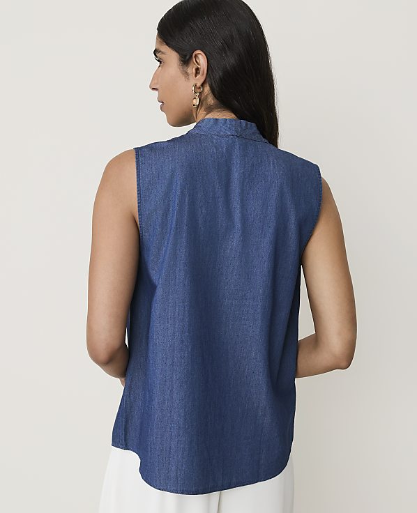 A woman in a denim top stands against a plain, light background.