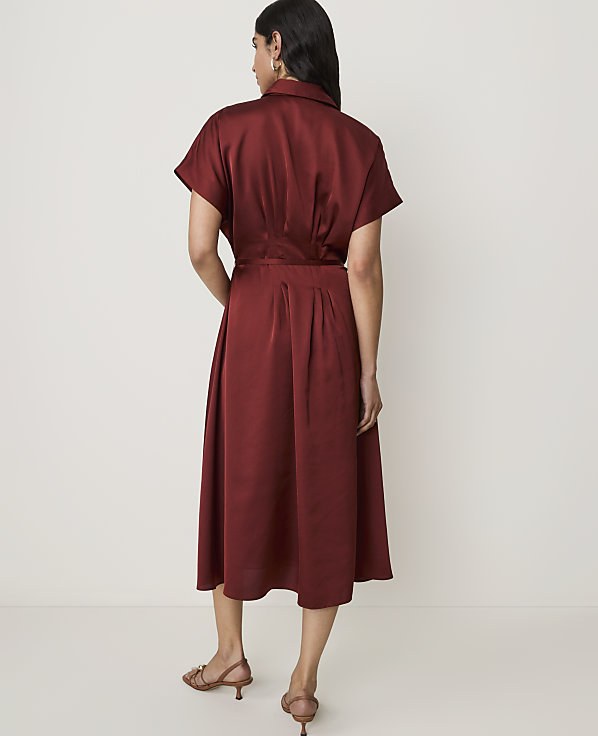 A woman in a maroon dress stands against a plain white background.