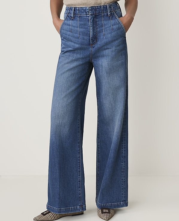 A person wearing wide-leg denim jeans stands against a plain white background.