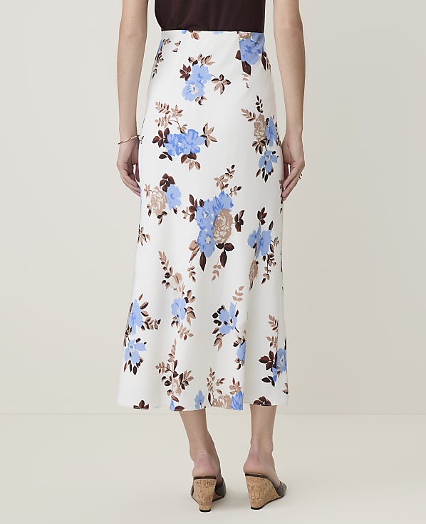 A woman in a floral skirt stands against a plain white background.