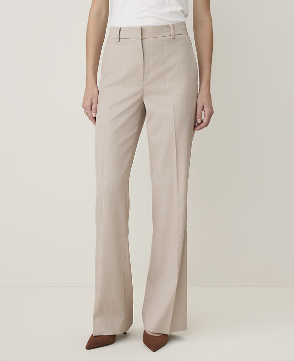 A person in beige pinstripe flared trousers and brown pointed-toe heels stands against a plain, light-colored background.