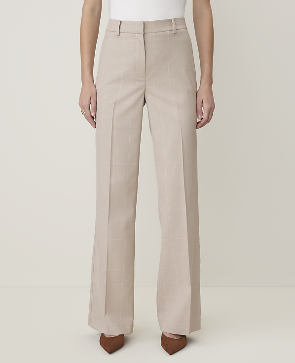 A person stands in light-colored, wide-leg trousers with subtle pinstripes, wearing brown pointed-toe heels against a plain, light background.