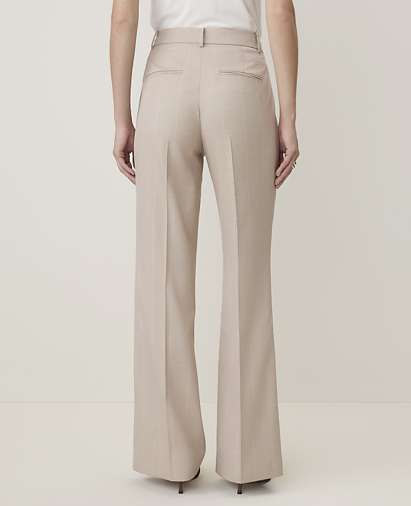 A person wearing beige wide-leg trousers stands against a plain, light-colored background.