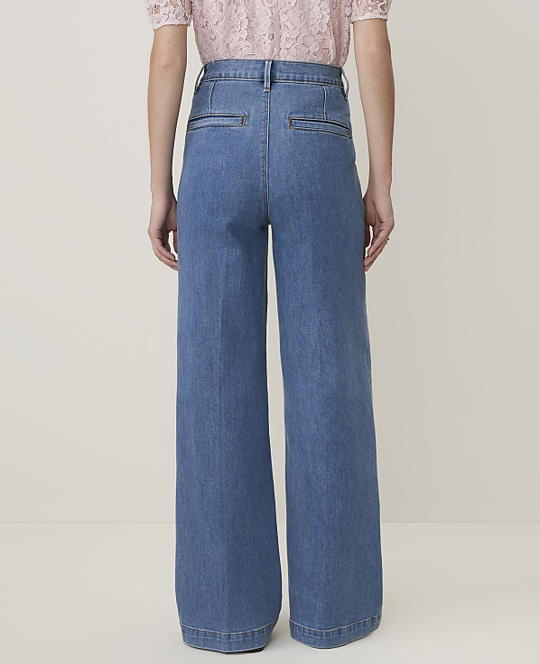 A person wearing wide-leg denim jeans stands against a plain, light-colored background.