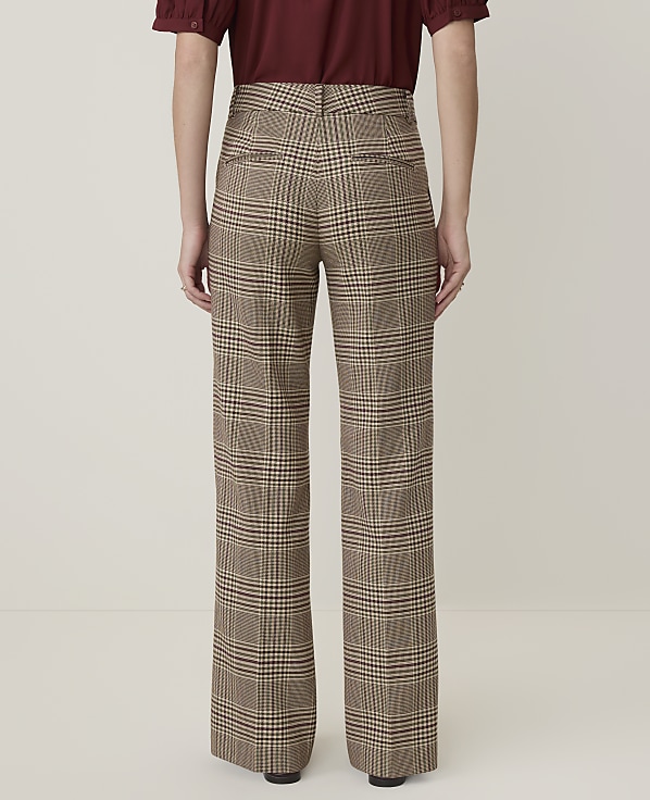 A person wearing plaid wide-leg pants stands against a plain, light-colored background.