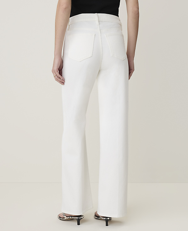 A person wearing white wide-leg jeans stands against a plain white background.