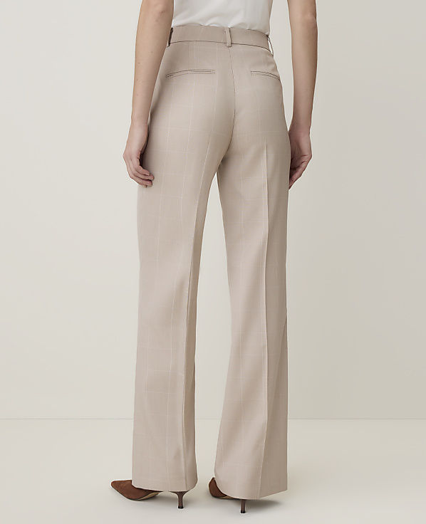 A person wearing beige wide-leg trousers stands against a plain, light-colored background.