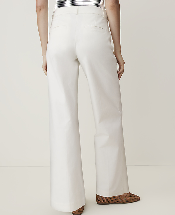 A person wearing white wide-leg pants and brown shoes stands against a plain white background.