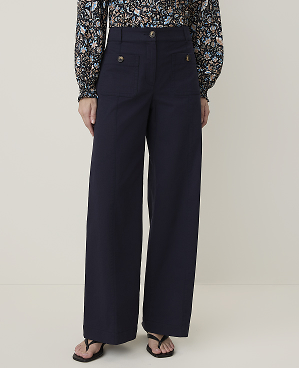 A person wearing navy wide-leg pants and a floral blouse stands against a plain, light-colored background.
