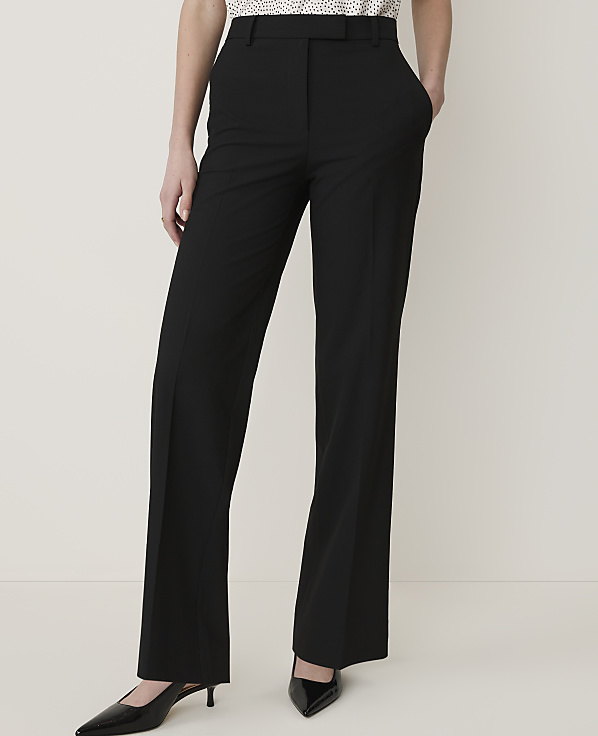 A person stands in black dress pants and pointed-toe heels against a plain white background.