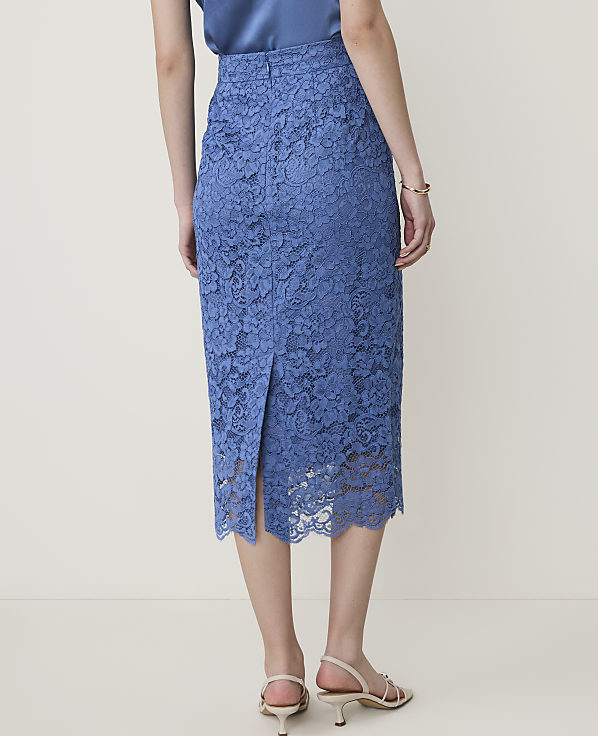 A woman in a blue lace skirt and white sandals stands against a plain, light-colored background.