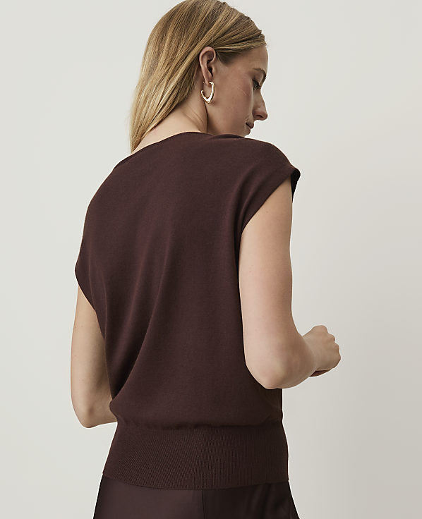 A woman in a brown sweater is shown from the back against a plain, light background.