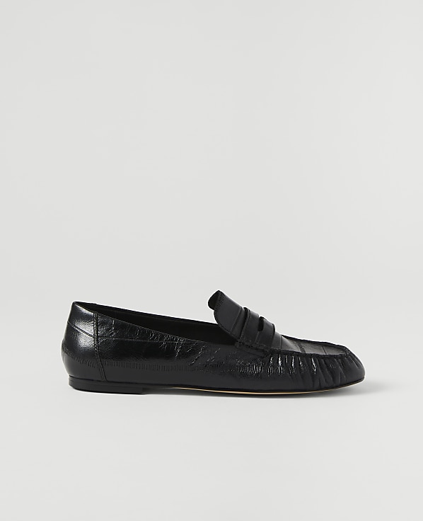 A black leather loafer rests on a plain white background.