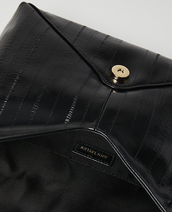 A glossy black clutch with a gold snap closure is laid open against a plain white background.
