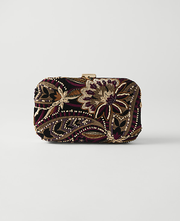 A richly embroidered clutch with floral and paisley patterns rests on a plain white background.