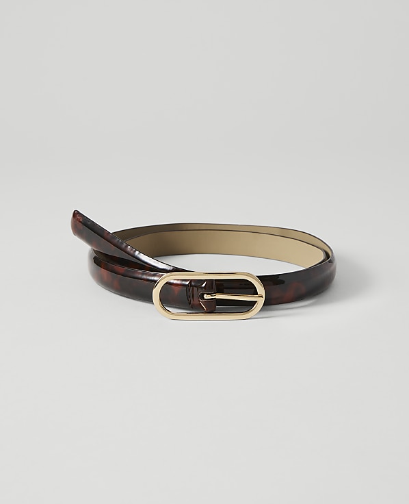A glossy, tortoiseshell-patterned belt with a gold oval buckle lies coiled on a plain white background.