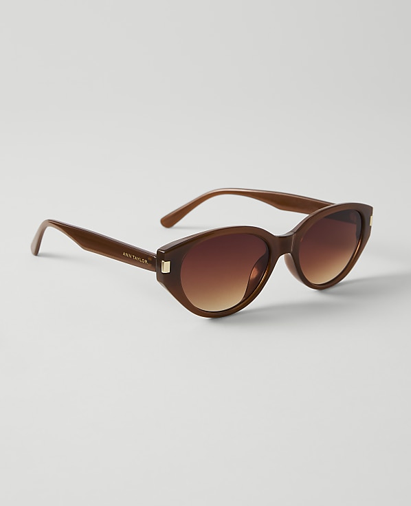 Brown cat-eye sunglasses with gradient lenses rest on a plain white background.