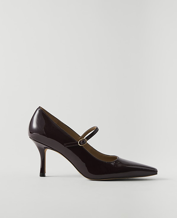 A glossy, dark red Mary Jane heel with a pointed toe rests on a plain, light gray background.