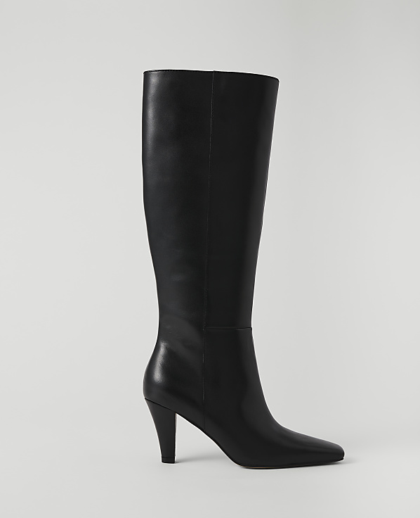 A black leather knee-high boot with a pointed toe and stiletto heel stands against a plain white background.