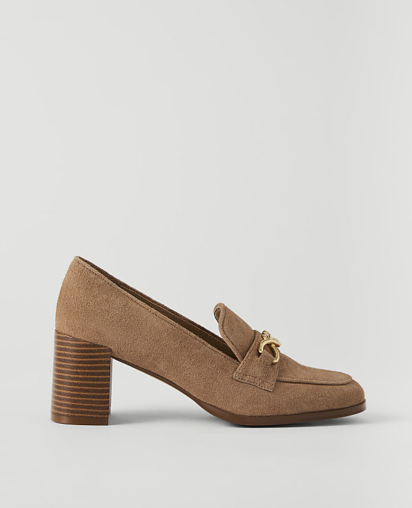 A tan suede loafer with a gold buckle sits on a plain white background.