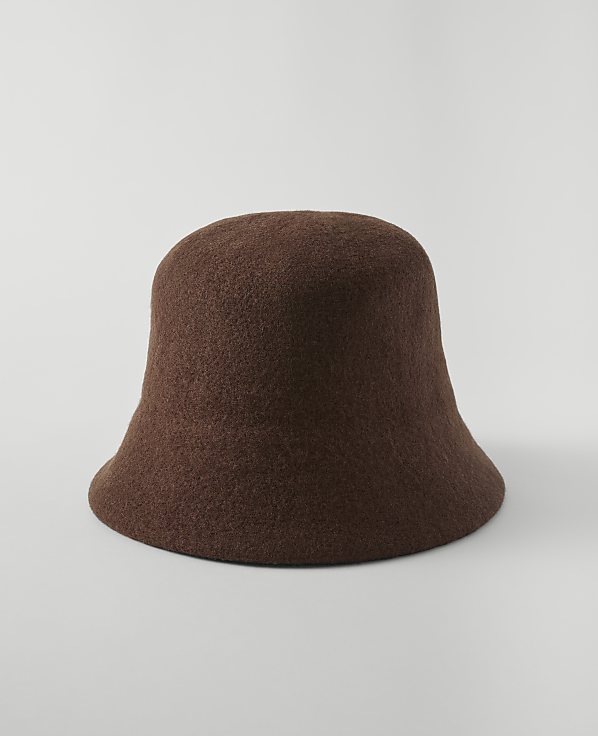 A brown felt bucket hat sits on a plain white surface against a seamless white background.