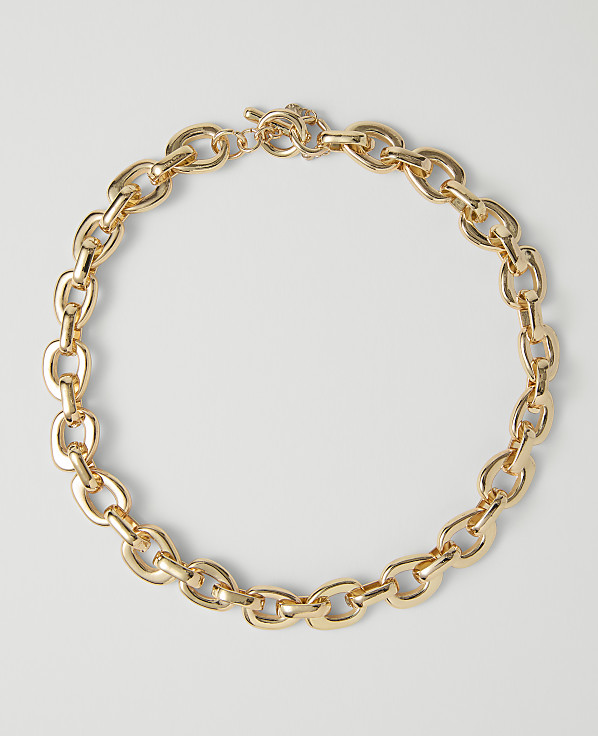 A chunky gold chain necklace with a toggle clasp rests on a plain white background.